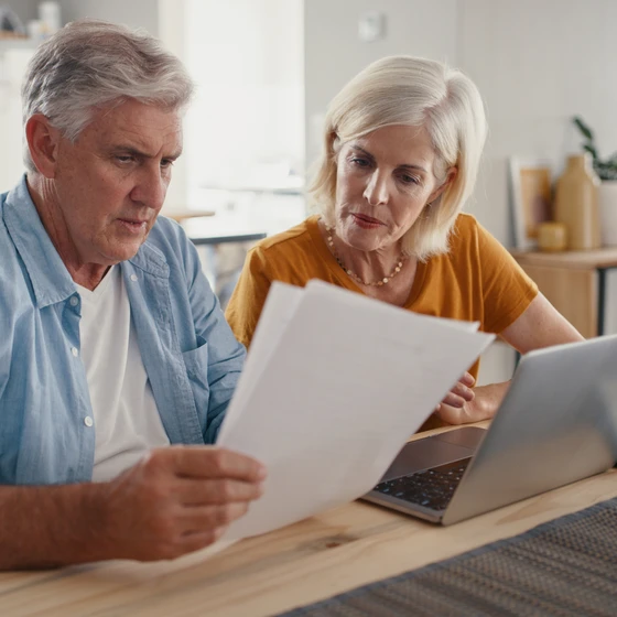 Un couple consulte un document devant un ordinateur pour s’informer sur la taxe TICE.