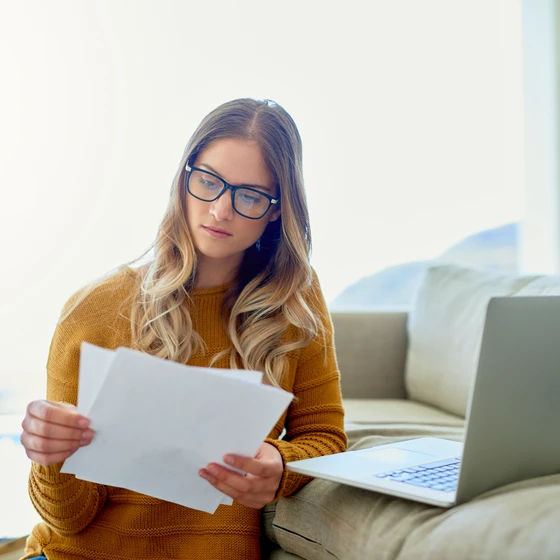 Une femme examine sa facture d’électricité devant son ordinateur pour optimiser ses dépenses.