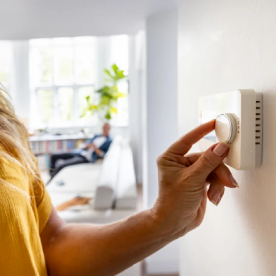 main tournant un thermostat pour ajuster la température