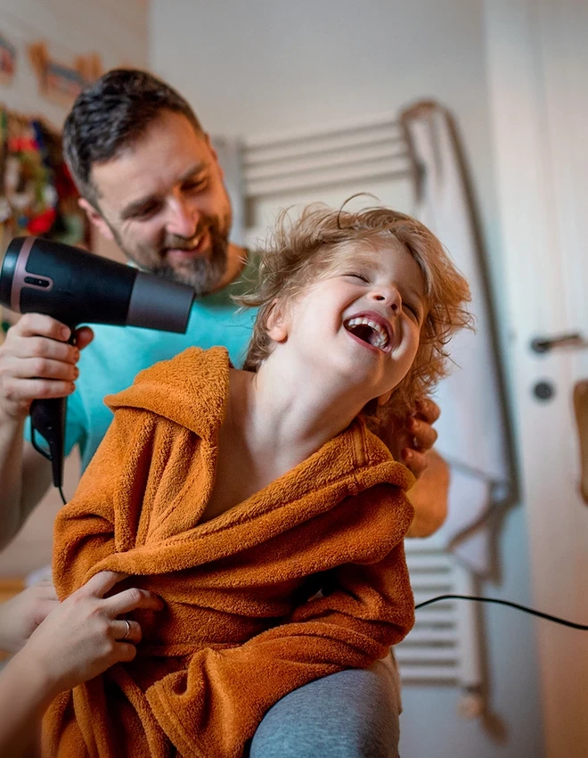 photo d'un homme séchant les cheveux d'un enfant avec un sèche cheveux