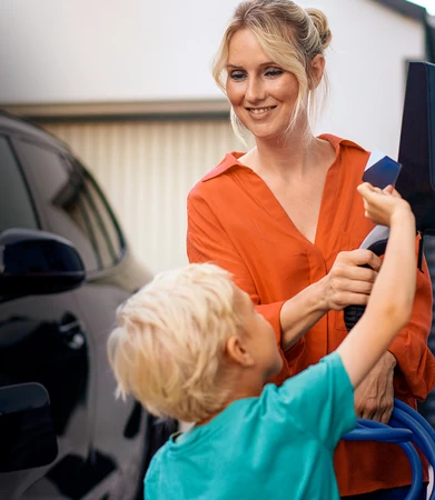 photo d'une femme accompagnée d'un enfant qui recharge une voiture électrique
